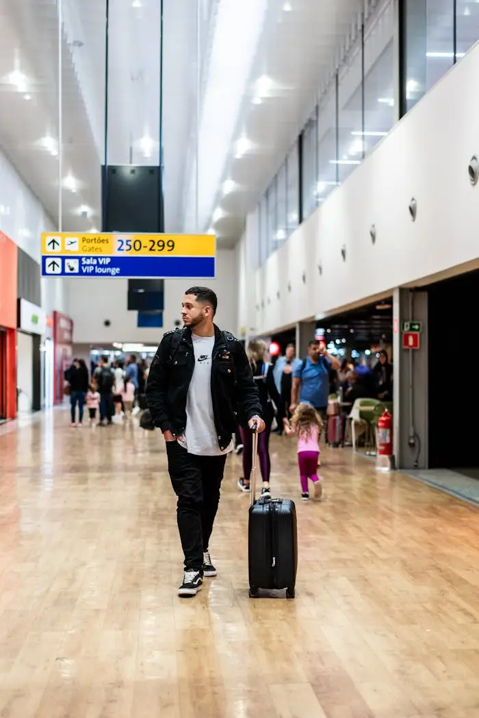 Services Man walking with luggage in a crowded airport terminal, heading to boarding gates.